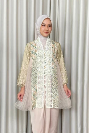Woman wearing a patterned kebaya by Kartinis Label and hijab against a plain background