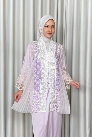 A woman wearing a traditional Kebaya Irish dress by Kartinis Label with batik and lace decorations, featuring a modern Kartinis Label silhouette.