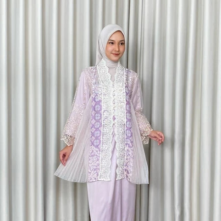 A woman wearing a traditional Kebaya Irish dress by Kartinis Label with batik and lace decorations, featuring a modern Kartinis Label silhouette.