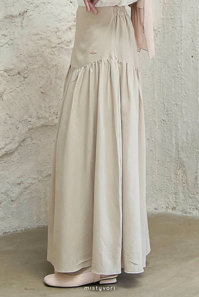 Beige long skirt by Mistyvori worn by a person against a textured wall.