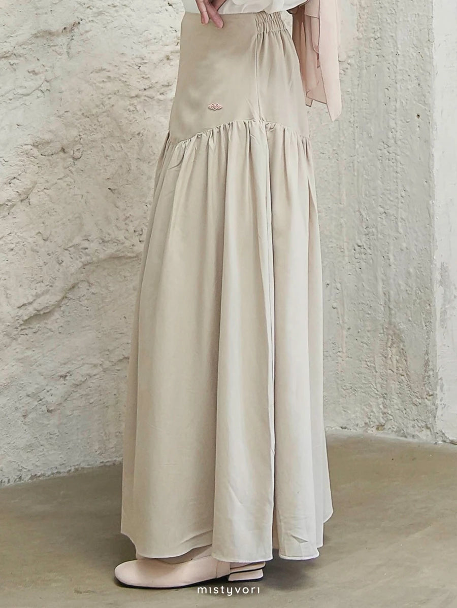 Beige long skirt by Mistyvori worn by a person against a textured wall.