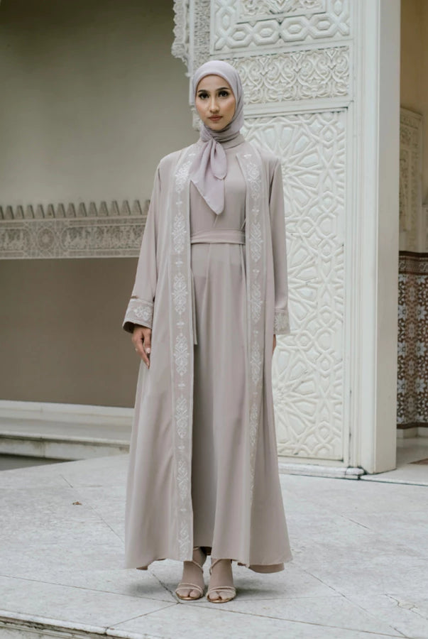 Woman in a beige abaya with white embroidery by Tubita.