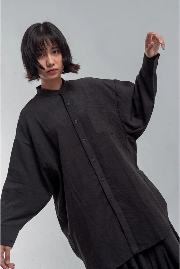 Person wearing a black oversized shirt by Yestoday against a gray background