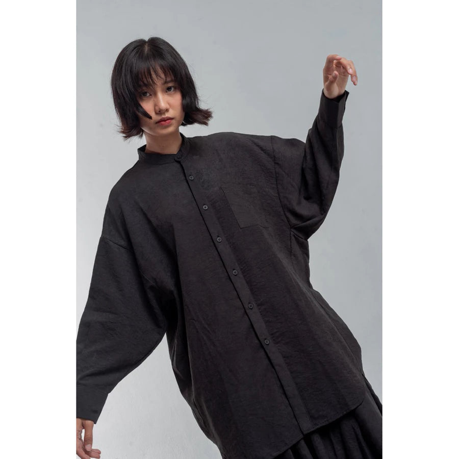 Person wearing a black oversized shirt by Yestoday against a gray background