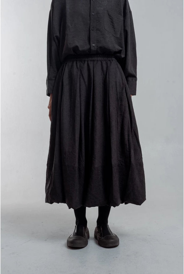 Person wearing a black outfit with a long skirt by Yestoday on a plain background