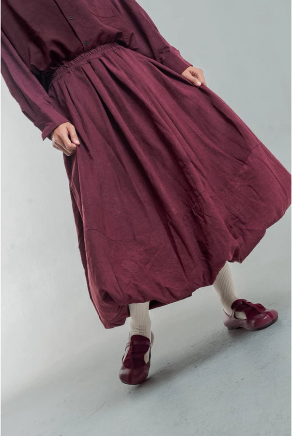Person wearing a burgundy skirt by Yestoday on a plain background