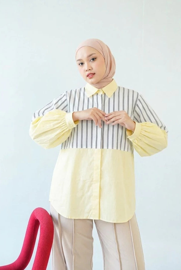 Woman wearing a striped shirt by Abame with yellow accents against a light blue background