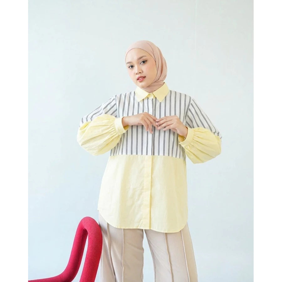 Woman wearing a striped shirt by Abame with yellow accents against a light blue background