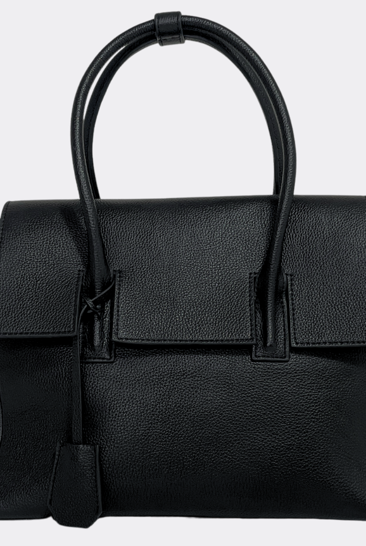 Black grain leather handbag by Aesthetic Pleasure with a strap on a light gray background