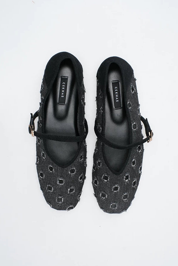A pair of black Mary Jane flatshoes with a textured, woven geometric pattern and black straps, shown from a top-down view on a white background.