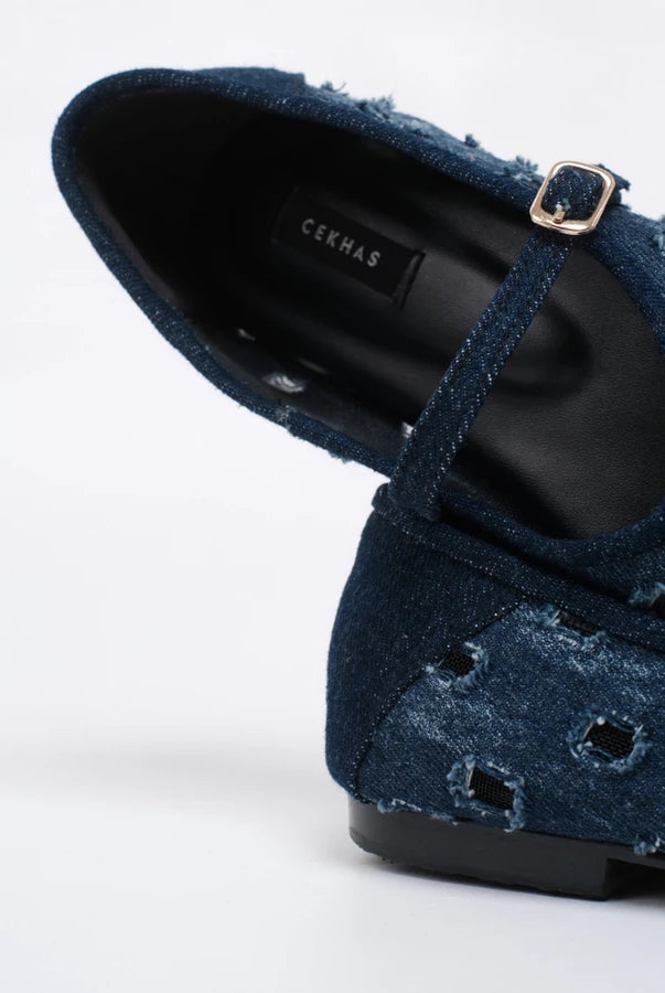 A close-up of a dark blue flatshoes with a strap and gold buckle, showing the CEKHAS brand label on the insole, set against a plain white background.