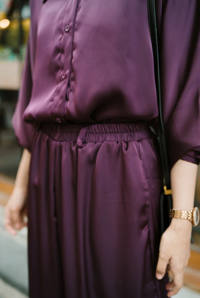 Person wearing a purple top and culottes with a blurred background.
Seseorang yang mengenakan atasan ungu dan celana kulot dengan latar belakang yang buram.