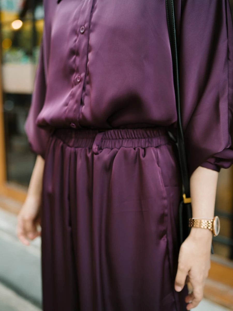 Person wearing a purple top and culottes with a blurred background.
Seseorang yang mengenakan atasan ungu dan celana kulot dengan latar belakang yang buram.