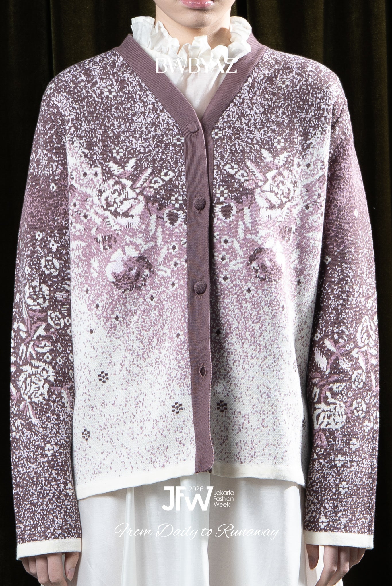 Person wearing a purple patterned cardigan by BWBYAZ over a white shirt against a dark background