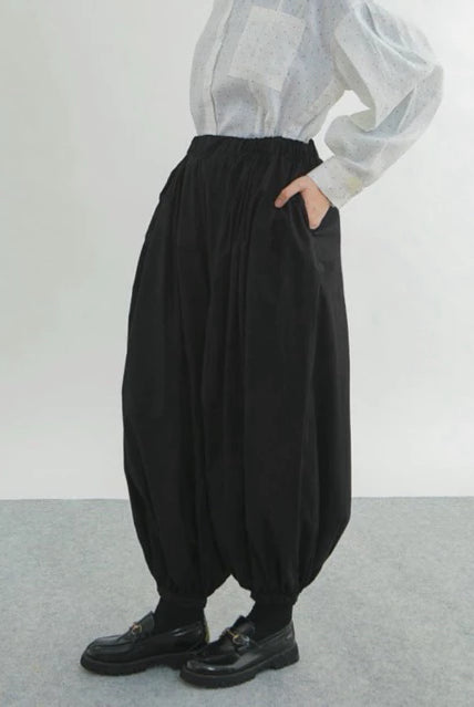 Person wearing black wide-leg pants by Yestoday and a light-colored shirt against a plain background