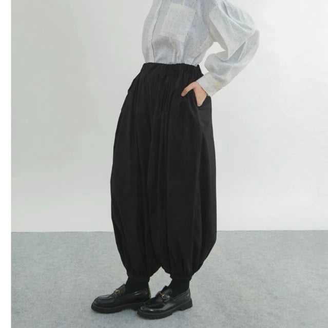 Person wearing black wide-leg pants by Yestoday and a light-colored shirt against a plain background