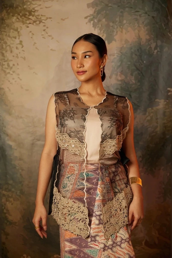 A woman wearing a traditional black kebaya vest by Kartinis Label with lace details and sequins.