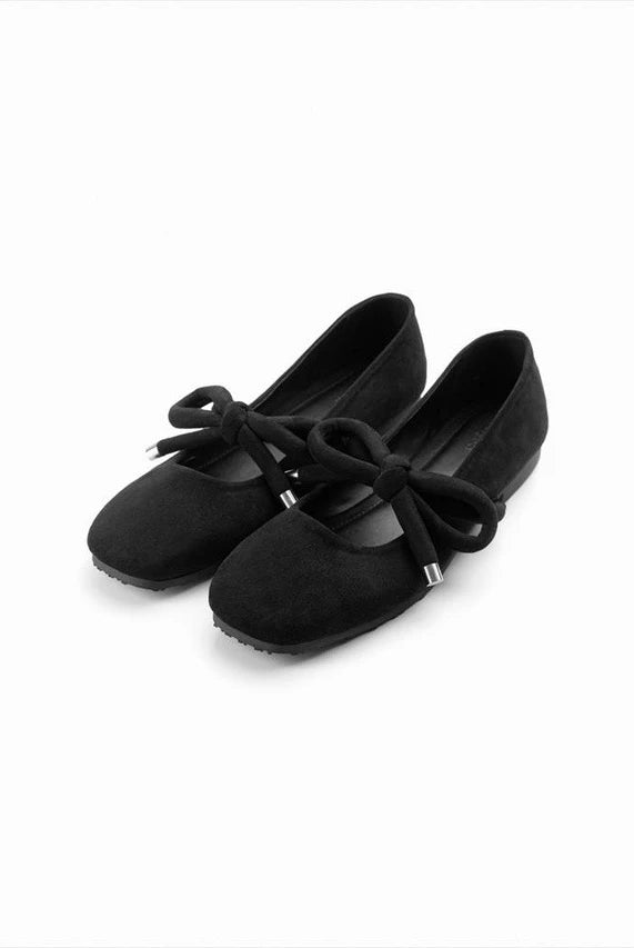 Pair of black flat shoes with a bow by Cajsa on a white background