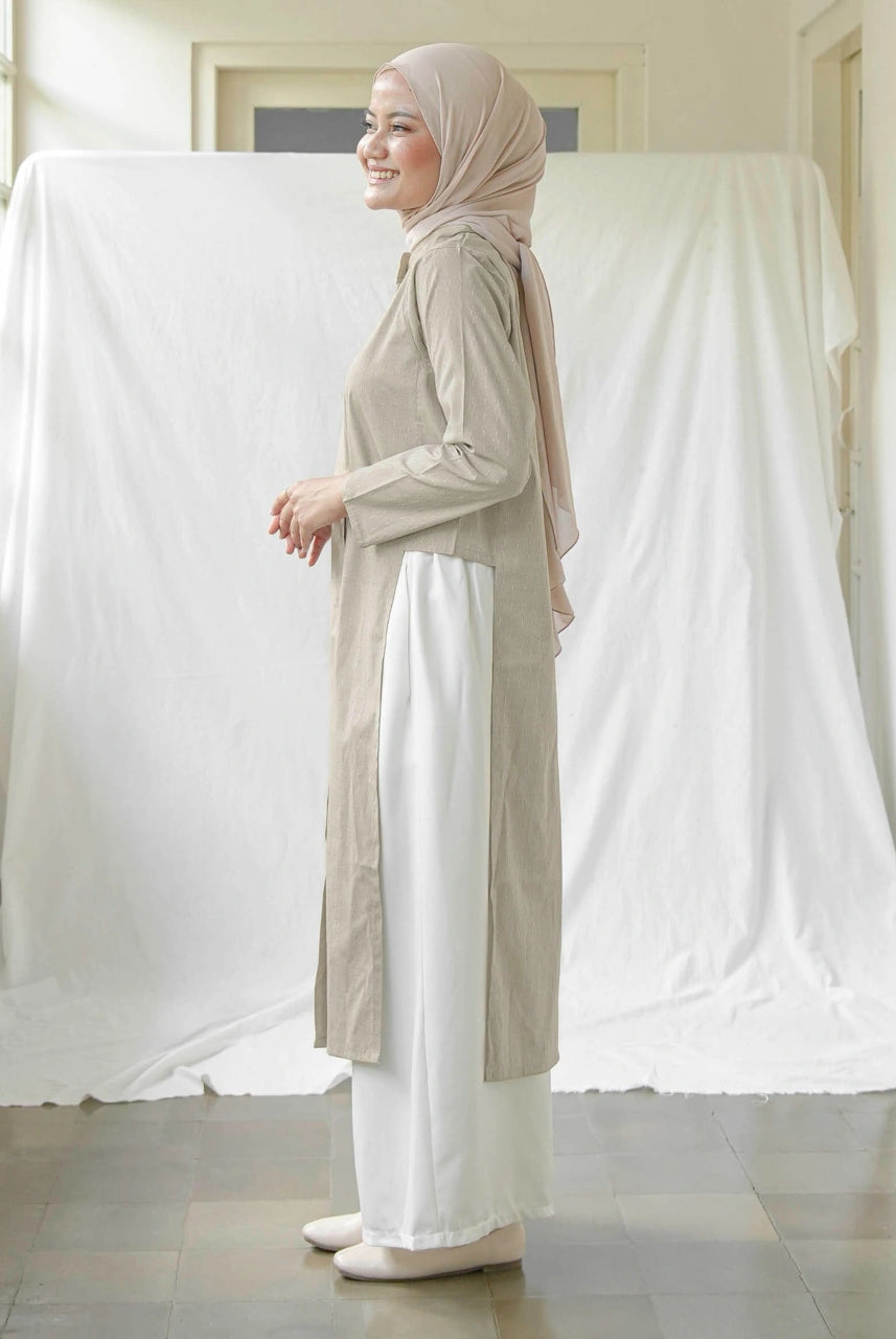 A woman wearing Mistyvori branded tunics in beige.
Seorang wanita memakai tunik berwarna beige dari brand Mistyvori.