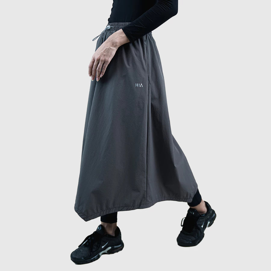 Person wearing a long dark gray skirt with 'HIA' branding on a light gray background
