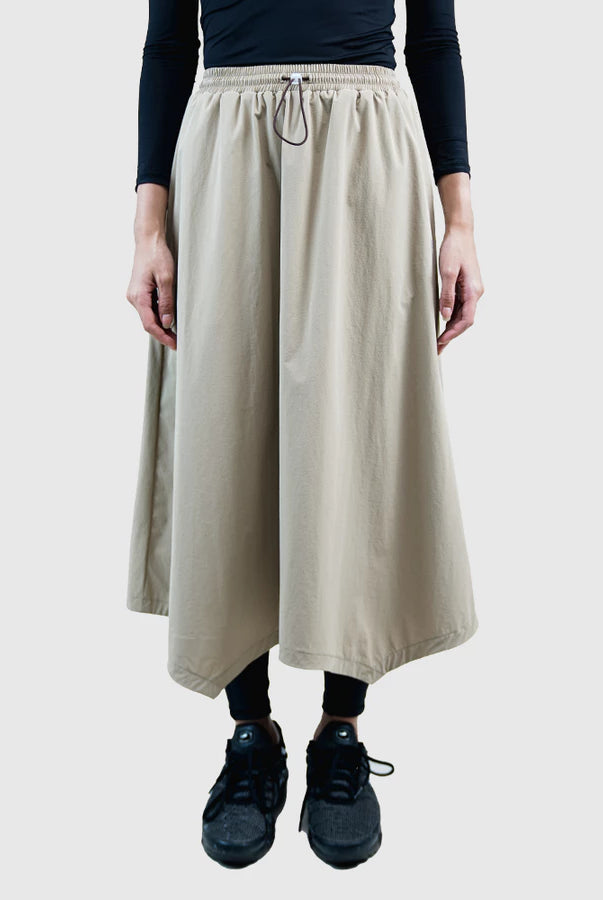 Person wearing a beige skirt by HIA with a plain background