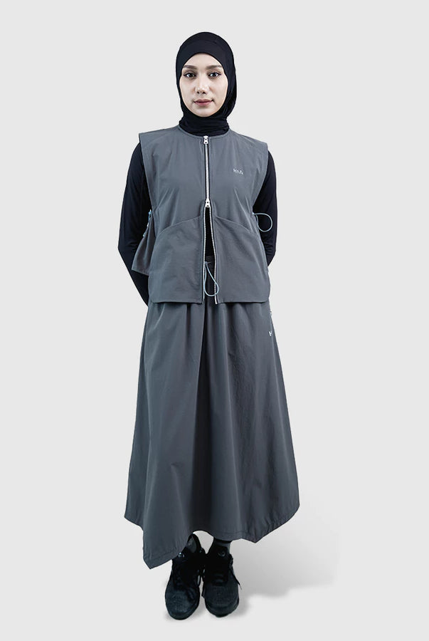 Person wearing a gray vest by HIA with a black hijab on a white background