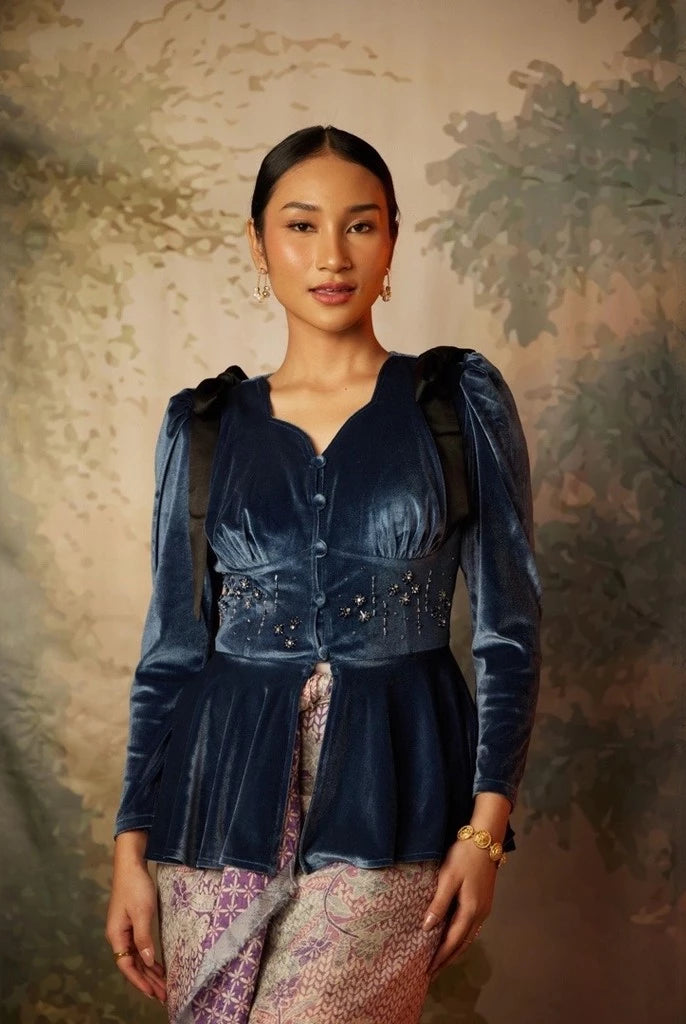 A woman wearing a long sleeve velvet top by Kartinis Label with pleated details and a fitted waist, in colors midnight blue.