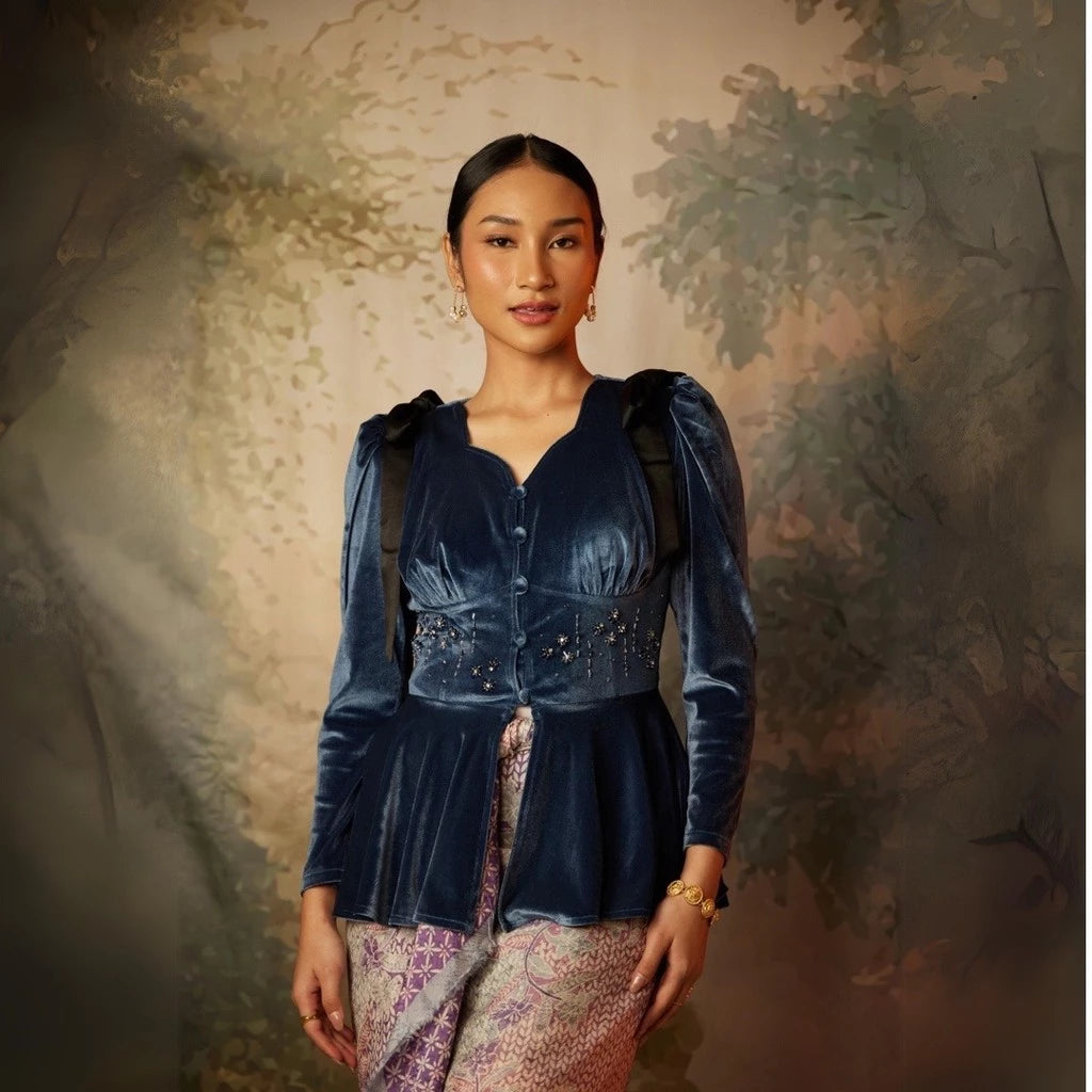 A woman wearing a long sleeve velvet top by Kartinis Label with pleated details and a fitted waist, in colors midnight blue.