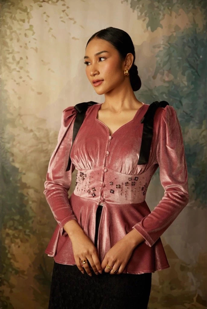 A woman wearing a long sleeve velvet top by Kartinis Label with pleated details and a fitted waist, in colors mauve.