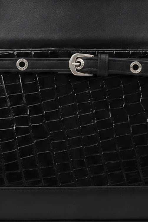 Close-up of a black textured leather handbag by Cekhas with a silver buckle.