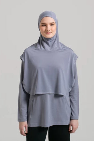 Person wearing a gray sport hijab by Noore and matching long-sleeve top on a light gray background