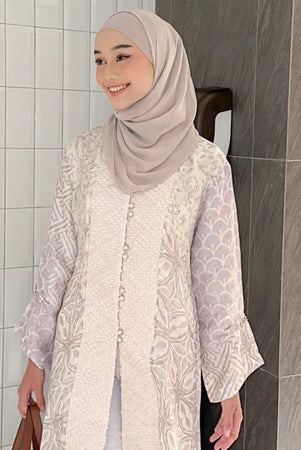 Seorang wanita memakai tunik bermotif batik berlengan panjang dari Kartinis Label.