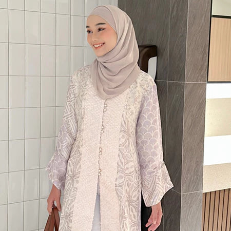 Seorang wanita memakai tunik bermotif batik berlengan panjang dari Kartinis Label.
