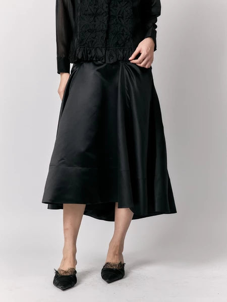 Person wearing a black outfit with a skirt by Studio Tui on a plain background