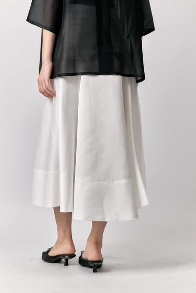 Person wearing a black top and white skirts by Studio Tui on a plain background
