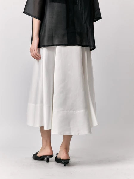 Person wearing a black top and white skirts by Studio Tui on a plain background