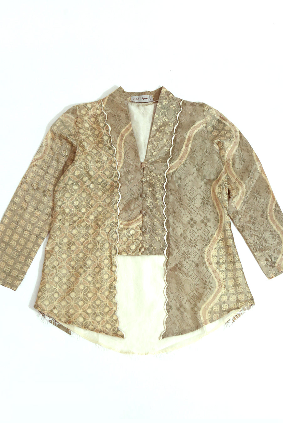 A traditional long sleeve Kutubaru kebaya blouse by Kartinis Label with beige and white batik patterns and embroidery details on the front.