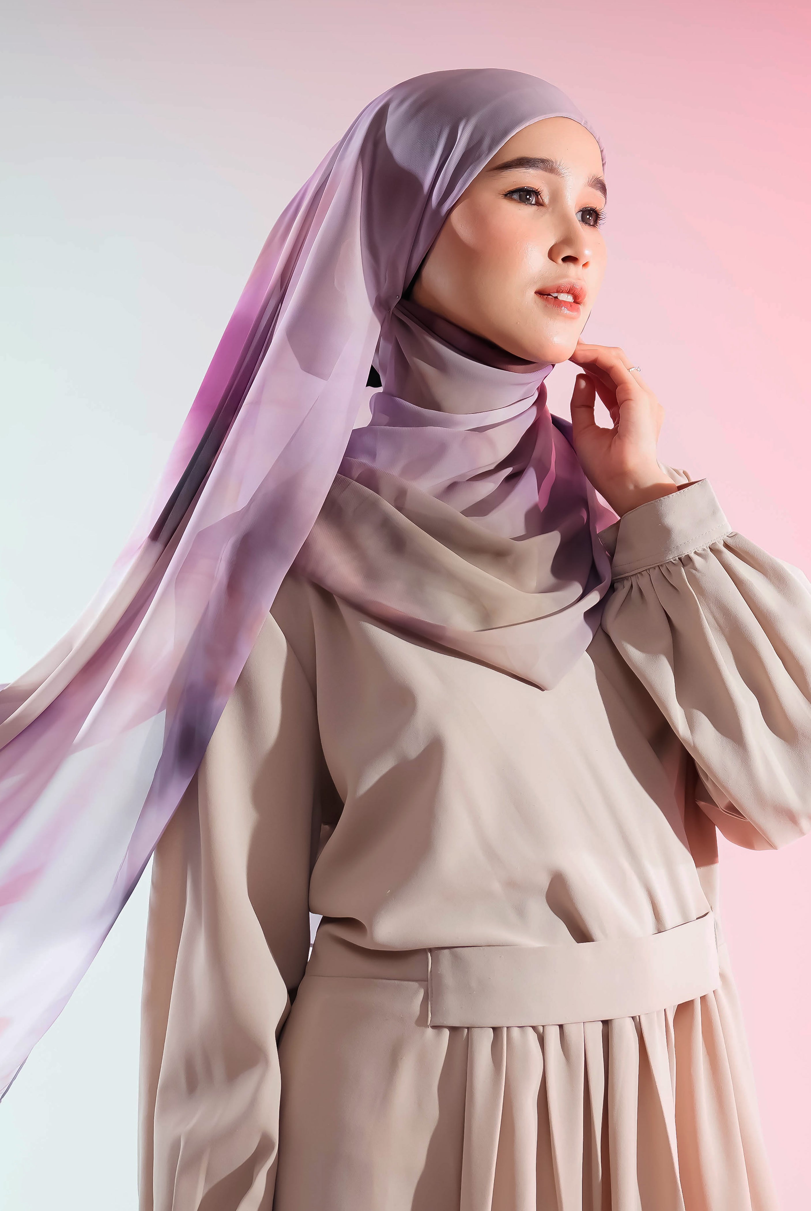 Woman wearing a beige outfit with a flowing pashmina by Puru Kambera against a pink background