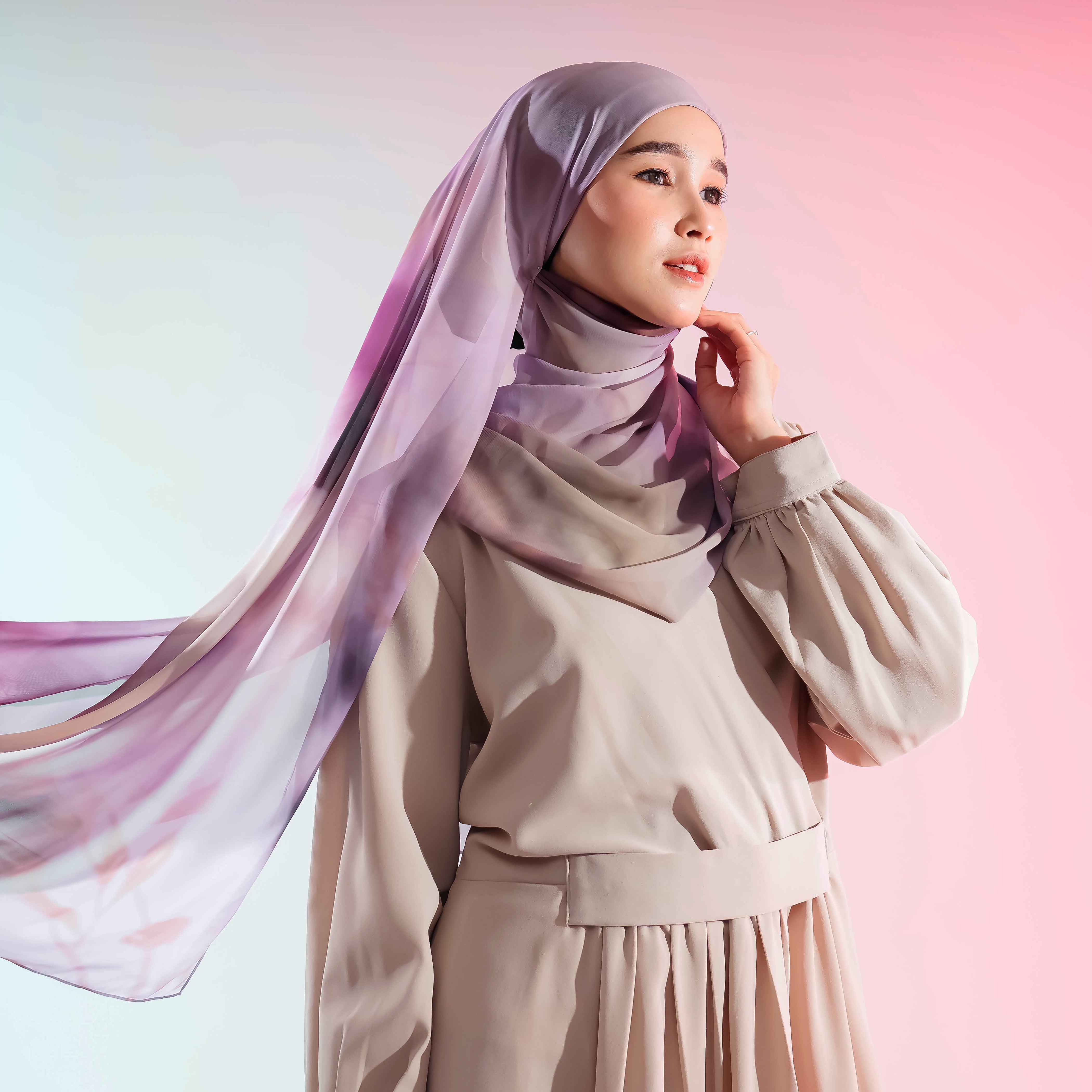 Woman wearing a beige outfit with a flowing pashmina by Puru Kambera against a pink background
