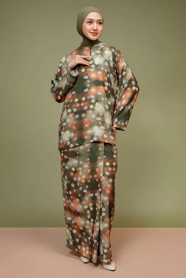 Woman wearing a patterned tunic set by Lozy Hijab against a green background.
Seorang wanita mengenakan set tunik bermotif dari Lozy Hijab dengan latar belakang hijau.