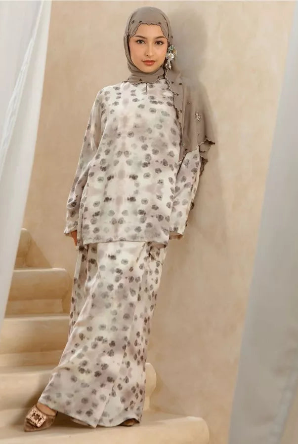 Woman wearing a floral tunic set standing on a staircase with curtains in the background.
Seorang wanita yang mengenakan set tunik bermotif bunga sedang berdiri di atas tangga dengan tirai di latar belakang.