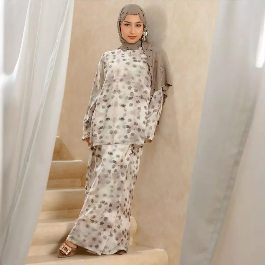 Woman wearing a floral tunic set standing on a staircase with curtains in the background.
Seorang wanita yang mengenakan set tunik bermotif bunga sedang berdiri di atas tangga dengan tirai di latar belakang.