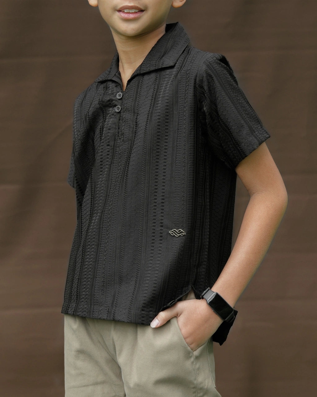 Child wearing a black patterned shirt by Mistyvori and beige pants against a brown background
