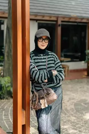 Woman wearing a striped knit sweaters by Haidee Orlin and hijab standing outdoors.