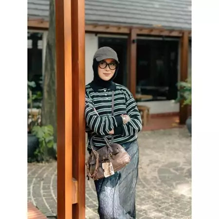 Woman wearing a striped knit sweaters by Haidee Orlin and hijab standing outdoors.