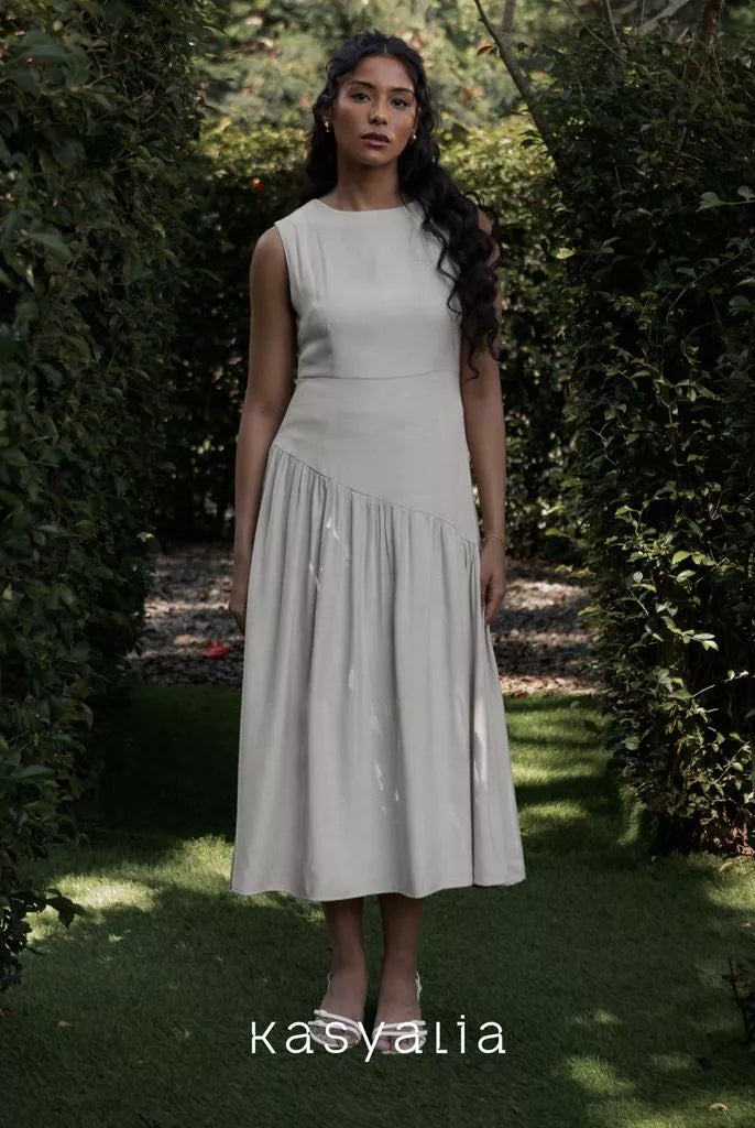 Woman in a white dress standing in a garden with 'kasyalia' branding.