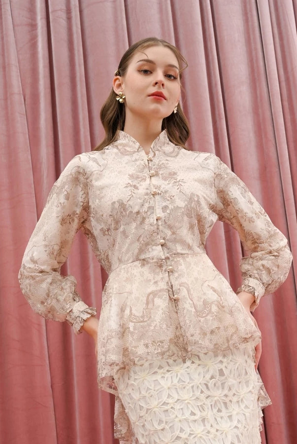 Woman wearing a lace beige blouse by Kasa Heritage against a pink curtain background