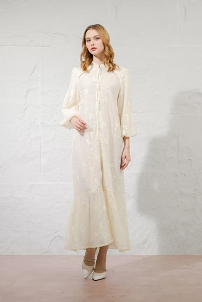 Woman wearing a long, light ivory-colored dress by Kasa Heritage against a white background