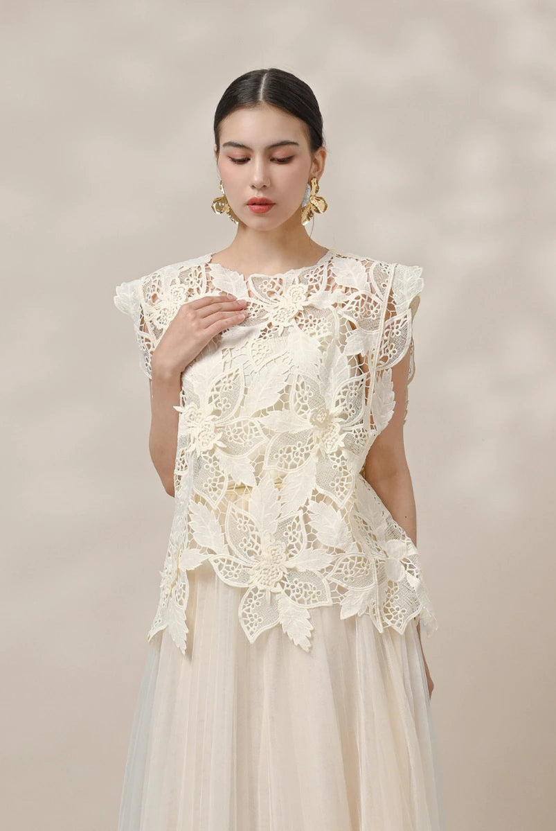 Woman wearing a beige lace vest by Kasa Heritage against a plain background