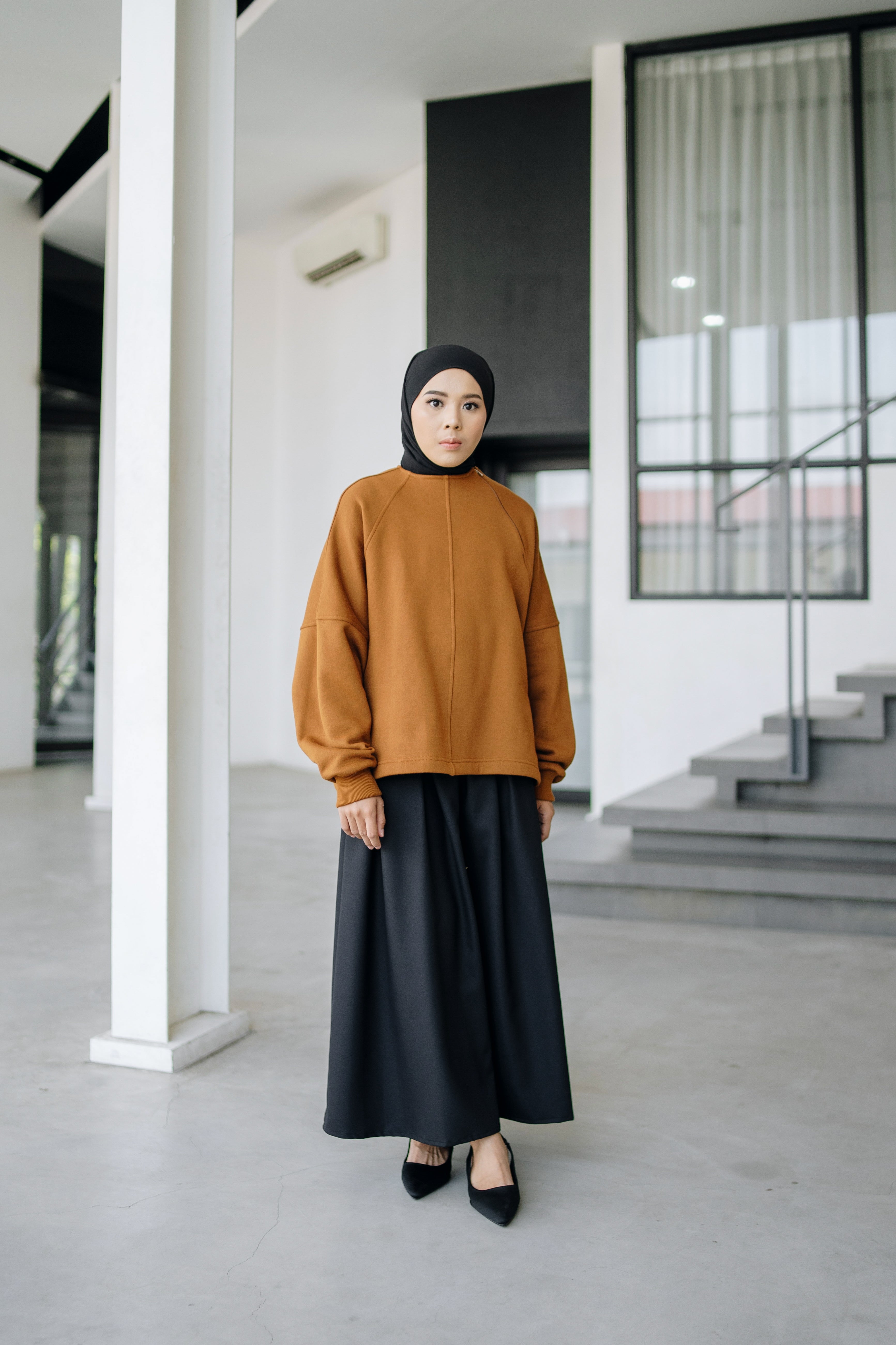 A person wearing an oversized sweater in cinnamon color by Swifter, paired with a long skirt.